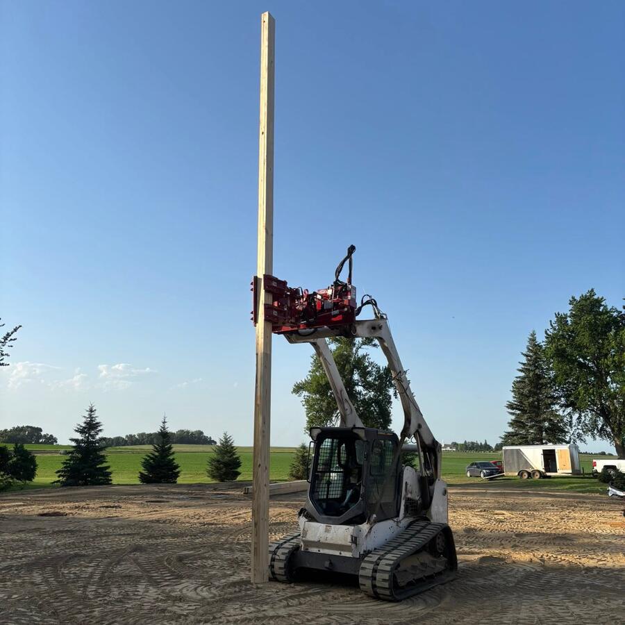 Skid steer setting the first pole on a Murphy pole shed build